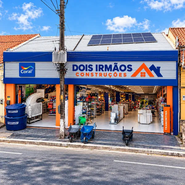 Fachada da Dois Irmãos Construções com caixas d'água e carrinhos de mão na calçada